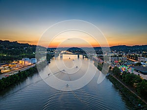 Aerial view of the sun setting behind boaters on the river