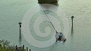 Aerial view of sunken sailboat on shallow bay waters after hurricane Ian in Manasota, Florida