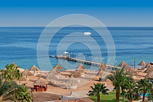 Aerial view of Sunny beach in tropical resort with palm trees and umbrellas, Sharm Al Sheikh, Egypt.