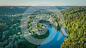 An aerial view A sunny summer evening The Gauja river flows between green forests and a bridge crosses the river.