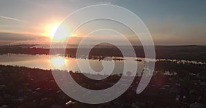 Aerial view. Sunset above the lake with small city on a shore. Industrial plant on a horizon. 4K