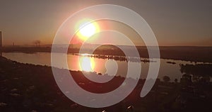 Aerial view. sunset above the lake with small city on a shore. Industrial plant on a horizon. 4K