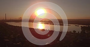 Aerial view. sunset above the lake with small city on a shore. Industrial plant on a horizon. 4K