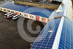 Aerial view of surface of blue photovoltaic solar panels mounted on industrial  building roof for producing clean ecological