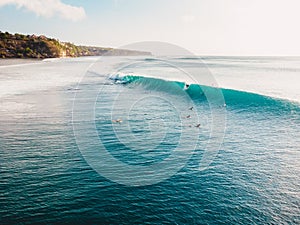 Aerial view with surfers and barrel blue wave in ocean