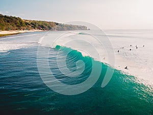 Aerial view with surfers and barrel turquoise wave in ocean. Bali