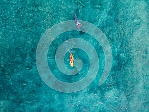 Aerial view of surfers swim on surfboard in blue ocean. Top view