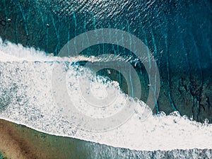 Aerial view of surfers in tropical blue ocean with waves at Bali. Top view