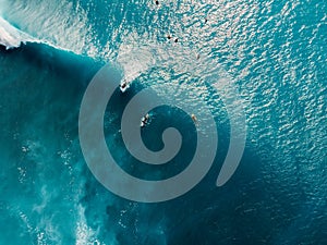 Aerial view of surfers in tropical blue ocean with waves at Bali. Top view