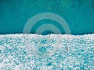 Aerial view of surfers and wave in tropical blue ocean