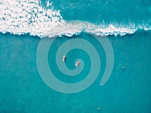 Aerial view of surfers and wave in tropical ocean. Top view