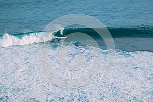 Aerial view with surfers and wave in tropical sea