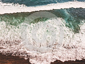 Aerial view of surfers in the waves of the Atlantic  ocean. Sandy beach. Panorama background shot on a drone. Selectivity focus