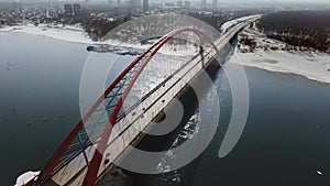 Aerial view of suspension bridge over blue river with city in the fog at backbround. Daylight. Shot from helicopter