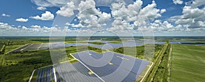 Aerial view of sustainable electric power plant between agricultural farm fields with solar photovoltaic panels for