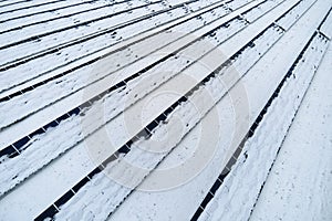 Aerial view of sustainable electrical power plant with solar photovoltaic panels covered with snow in winter for