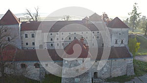 Aerial view of Svirzh castle near Lviv, Ukraine at dawn. Lake, morning fog and surrounding landscape at sunrise.