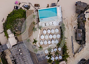 Aerial view of swimming pool on the beach with umbrellas for relaxing. A resort on Melasti Beach, Bali, Indonesia.