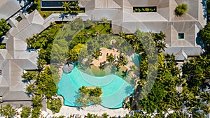 Aerial view of the swimming pool among buildings and trees at the tropical island