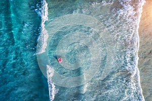 Aerial view of a swimming woman in blue sea with waves