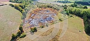 Aerial view of the tailings pile of an ore quarry, from which red-colored liquid flows into a ditch