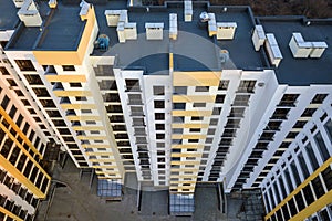 Aerial view of tall apartment building complex. Blue flat roof with chimneys, inner yard, row of windows. Drone photography