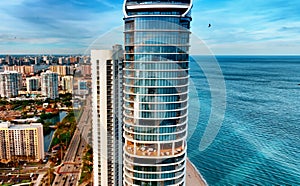 Aerial View of Tall Building Next to the Ocean in Miami, USA. This image depicts an aerial view of a tall building situated