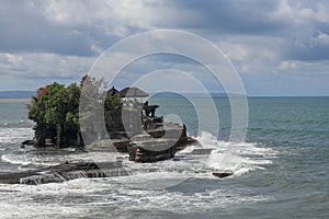 Aerial view of Tanah Lot temple on cliff in Indian ocean. Waves are breaking on a rock cliff off the coast of Bali. Hindu temple