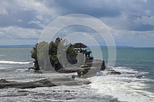 Aerial view of Tanah Lot temple on cliff in Indian ocean. Waves are breaking on a rock cliff off the coast of Bali. Hindu temple