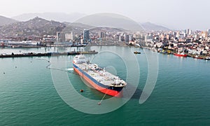 Aerial view of tanker ship in clear turquoise waters near coastal cityscape
