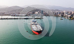 Aerial view of tanker ship in clear turquoise waters near coastal cityscape