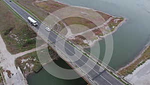 Aerial view of a tanker truck approaching a bridge on a shoreline highway