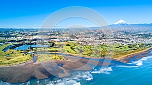 Aerial view on Taranaki coastline with a small river and New Plymouth and Mount Taranaki on the background. Taranaki region, New Z