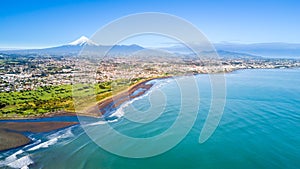 Aerial view on Taranaki coastline with a small river and New Plymouth and Mount Taranaki on the background. Taranaki region, New Z