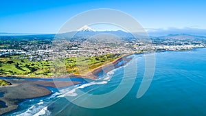 Aerial view on Taranaki coastline with a small river and New Plymouth and Mount Taranaki on the background. Taranaki region, New Z