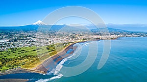 Aerial view on Taranaki coastline with a small river and New Plymouth and Mount Taranaki on the background. Taranaki region, New Z