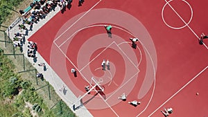 Aerial view of teenagers playing basketball on the summer basketball court.