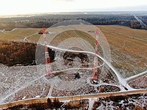 Aerial view telecommunication towers of mobile communication on the background of green field is covered with white snow.