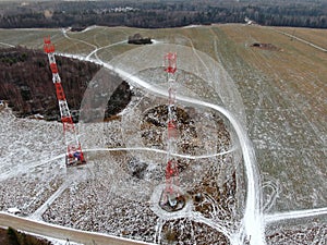 Aerial view telecommunication towers of mobile communication on the background of green field is covered with white snow.