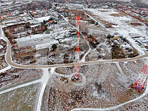 Aerial view telecommunication towers of mobile communication on the background of green field is covered with white snow.