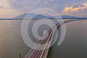 Aerial view of Thai local train on railway bridge at Pa Sak Jolasid Dam, the biggest reservoir in central Thailand, in Lopburi