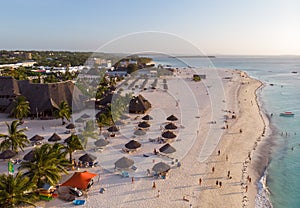 Aerial view of Thatched Roof Umbrellas Pattern on Wide Coastal line of White Sand of Kendwa Beach in Kendwa village