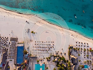 Aerial view of Thatched Roof Umbrellas Pattern on Wide Coastal line of White Sand of Kendwa Beach in Kendwa village