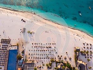 Aerial view of Thatched Roof Umbrellas Pattern on Wide Coastal line of White Sand of Kendwa Beach in Kendwa village