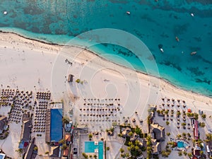 Aerial view of Thatched Roof Umbrellas Pattern on Wide Coastal line of White Sand of Kendwa Beach in Kendwa village