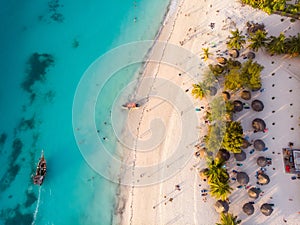 Aerial view of Thatched Roof Umbrellas Pattern on Wide Coastal line of White Sand of Kendwa Beach in Kendwa village