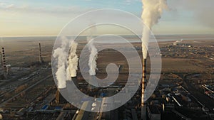 Aerial view of thermal power plant. Drone flies over chimney smoke pipes and cooling towers of industrial area on sunset