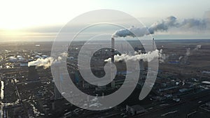 Aerial view of thermal power plant. Drone flies over chimney smoke pipes and cooling towers of industrial area on sunset