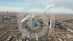 Aerial view of thermal power plant. Drone flies over chimney smoke pipes and cooling towers of industrial area on sunset