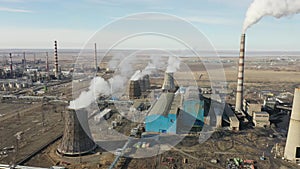 Aerial view of thermal power plant. Drone flies over chimney smoke pipes and cooling towers of industrial area on sunset